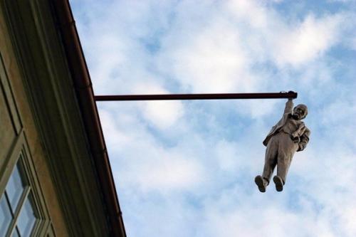 На выступающем элементе крыши одного из домов Праги можно увидеть скульптуру висящего человека в костюме.