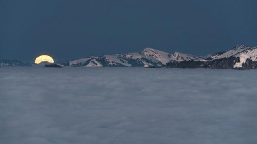 Суперлуние над долиной Рейна, укрытой морем облаков, и горными цепями в форарльберге, Австрия.